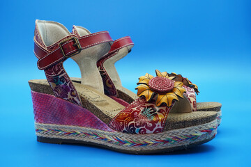 Bright summer women's sandals made of genuine leather, wedge heels, decorated with a large flower. Blue background.