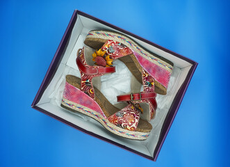 Box with bright summer women's sandals made of genuine leather, wedge heels, decorated with a large flower.