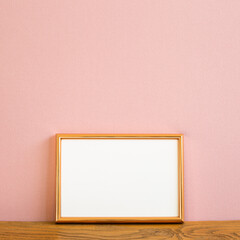 Empty picture frame on wooden table. pink background