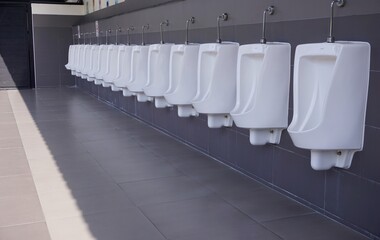 Toilets are white in the male toilets with urinals arranged neatly along the wall.