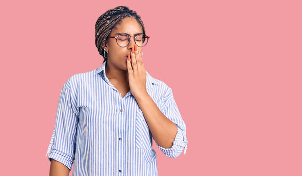 Young african american woman with braids wearing casual clothes and glasses bored yawning tired covering mouth with hand. restless and sleepiness.
