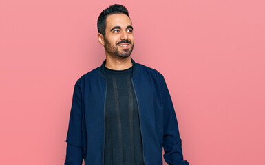Obraz premium Young hispanic man wearing casual clothes looking away to side with smile on face, natural expression. laughing confident.
