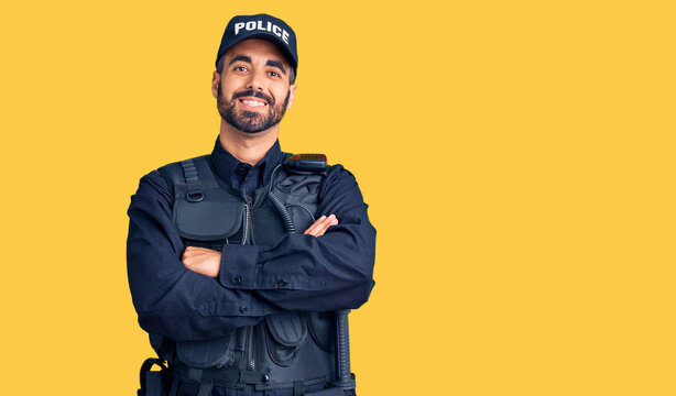 Young hispanic man wearing police uniform happy face smiling with crossed arms looking at the camera. positive person.