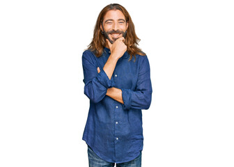 Attractive man with long hair and beard wearing casual clothes looking confident at the camera smiling with crossed arms and hand raised on chin. thinking positive.