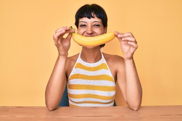 Brunette teenager girl holding banana like funny smile smiling with a happy and cool smile on face....