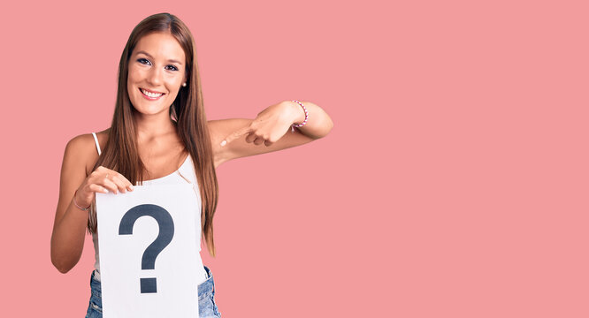 Young beautiful hispanic woman holding question mark pointing finger to one self smiling happy and proud