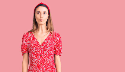 Obraz premium Young beautiful girl wearing dress and diadem making fish face with lips, crazy and comical gesture. funny expression.