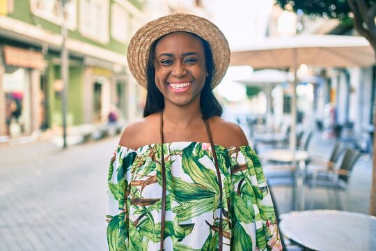 Young african american tourist woman on vacation smiling happy using vintage camera at the city.