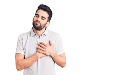 Young handsome man with beard wearing casual polo smiling with hands on chest with closed eyes and grateful gesture on face. health concept.