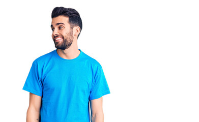 Fototapeta premium Young handsome man with beard wearing casual t-shirt looking away to side with smile on face, natural expression. laughing confident.