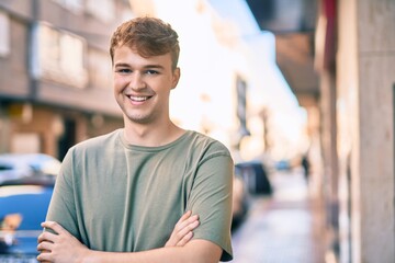 Fototapeta premium Young caucasian man with arms crossed smiling happy at the city.