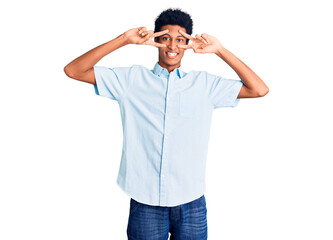 Fototapeta premium Young african american man wearing casual clothes doing peace symbol with fingers over face, smiling cheerful showing victory