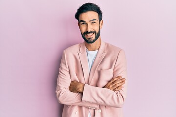 Young hispanic man wearing business jacket happy face smiling with crossed arms looking at the camera. positive person.