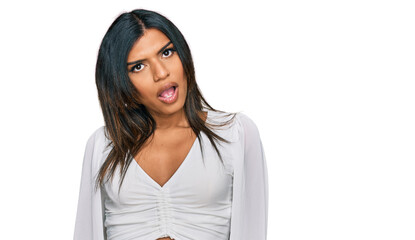 Obraz premium Young latin transsexual transgender woman wearing casual clothes in shock face, looking skeptical and sarcastic, surprised with open mouth