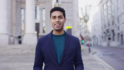 Young male presenter walking and talking towards camera in the city