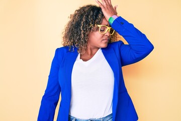 Young african american plus size woman wearing business jacket and glasses surprised with hand on...