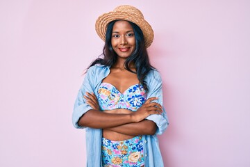 Young indian girl wearing bikini and summer hat happy face smiling with crossed arms looking at the camera. positive person.