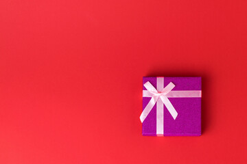 Top view of a gift box with a ribbon on a red background.