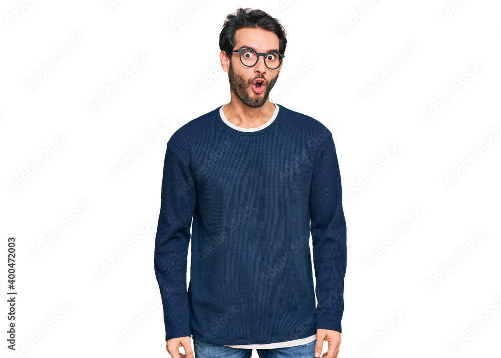 Sticker Young hispanic man wearing casual clothes and glasses afraid and shocked with surprise expression, fear and excited face.