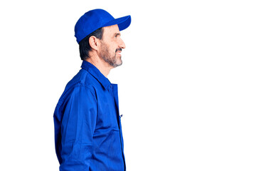 Middle age handsome man wearing mechanic uniform looking to side, relax profile pose with natural face and confident smile.