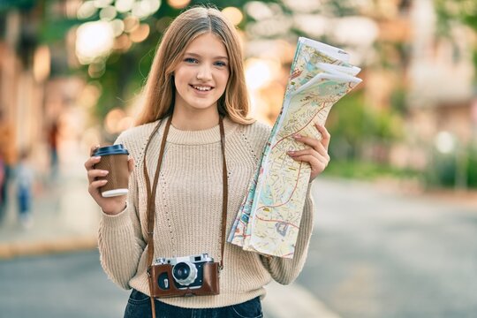Beautiful caucasian tourist teenager drinking coffee holding map at the city.