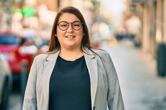 Young hispanic plus size businesswoman smiling happy standing at the city.