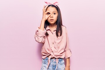 Beautiful child girl wearing casual clothes doing ok gesture shocked with surprised face, eye looking through fingers. unbelieving expression.