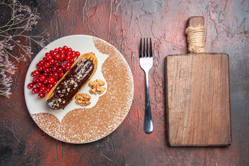 top view yummy choco eclairs with red berries on a dark background cake pie dessert sweet