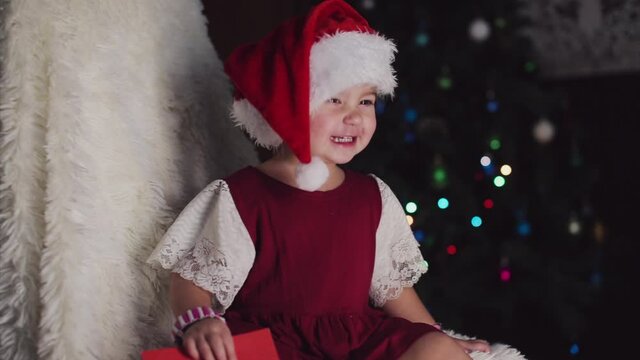 a child in red clothes is sitting waiting for the new year. the concept of celebrating Christmas at midnight. holiday costume. a girl writes a letter to Santa Claus. wish list