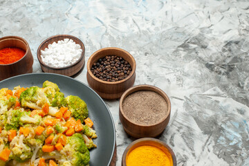 Half shot of healthy vegetable salad on wooden cutting board and spices on white background