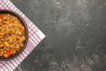top view roasted eggplant salad in bowl on pink white checkered tablecloth on dark background copy place