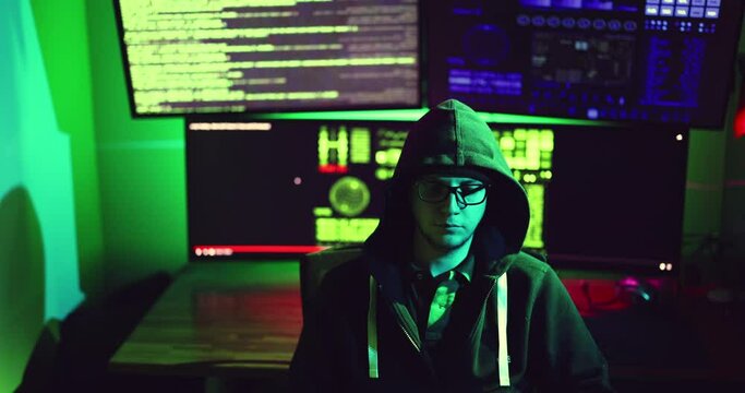 Young nerdy hacker wearing glasses sits at computer hacking, or malware servers firewall or phishing credit cards. Surveillance privacy GDPR concept security. Online internet technology cyber crime
