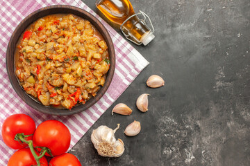 top view roasted eggplant salad in bowl on pink white checkered tablecloth tomatoes oil garlic on dark background copy space