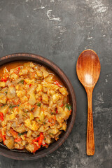 top view roasted aubergine salad in bowl wooden spoon on dark background
