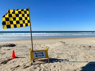 Warning flag blowing on the beach on sunny day