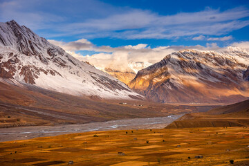 Serene Landscape of Spiti river valley with agriculture fields and snow capped mountains in background during sunrise near Kaza town in Lahaul and Spiti district of Himachal Pradesh, India.