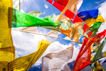 Colorful prayer flags flying in winds with blue sky and Himalayas mountains in background at Hikkim village in Spiti region of Himachal Pradesh, India.