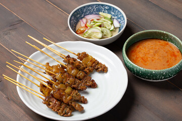 beef satay grilled and spicy peanut sauce on wooden background