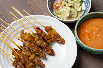 beef satay grilled and spicy peanut sauce on wooden background.