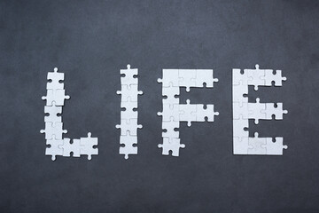 Word "Life" laid out by mosaic puzzle on cold dark grunge background. Life is difficult concept. Life is puzzle