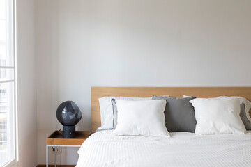 Minimal contemporary style bedroom with white fabric bed set and side table lamp.