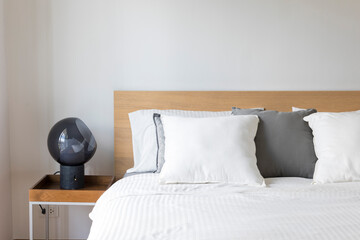 Minimal contemporary style bedroom with white fabric bed set and side table lamp.