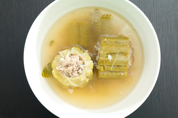 Thai food, bitter gourd soup with pork in a bowl on wooden table.