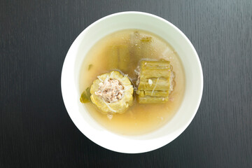 Thai food, bitter gourd soup with pork in a bowl on wooden table.