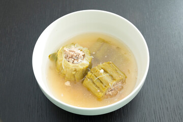 Thai food, bitter gourd soup with pork in a bowl on wooden table.