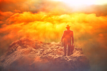 Surreal image of mysterious man walking alone in field during sunset