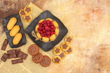 Overhead view of tasty cake different biscuits on brown plate on mixed color background