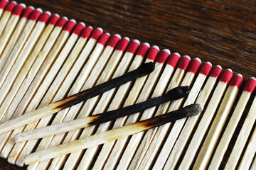 A close up image of a several wooden matches on a wooden background. 