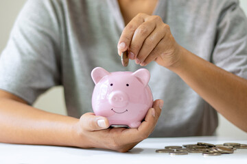 Obraz na płótnie Canvas Women put coins in pink piggy bank and save money to plan their future retirement fund ideas.