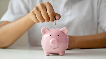 Women put silver coins into piglets to save money and save money for future investment. Financial...